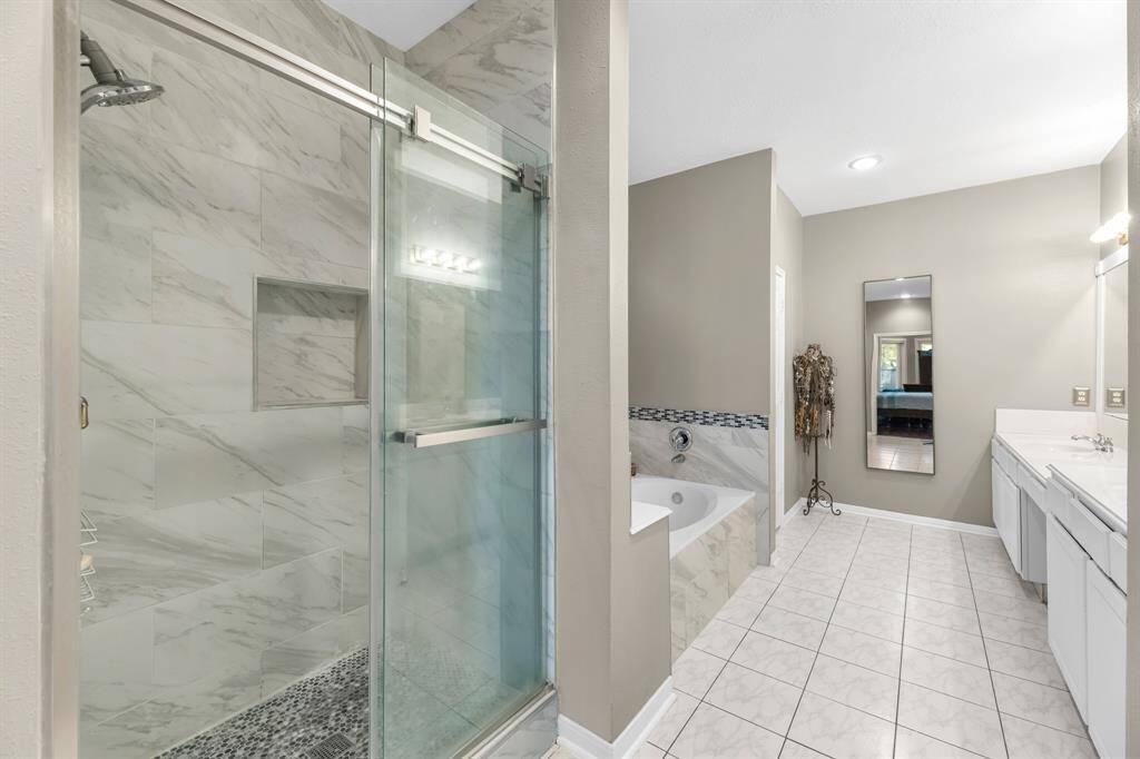 Indulge in this elegant bathroom retreat featuring a luxurious walk-in shower, soaking tub, and sleek double vanity. Perfect for unwinding in style.