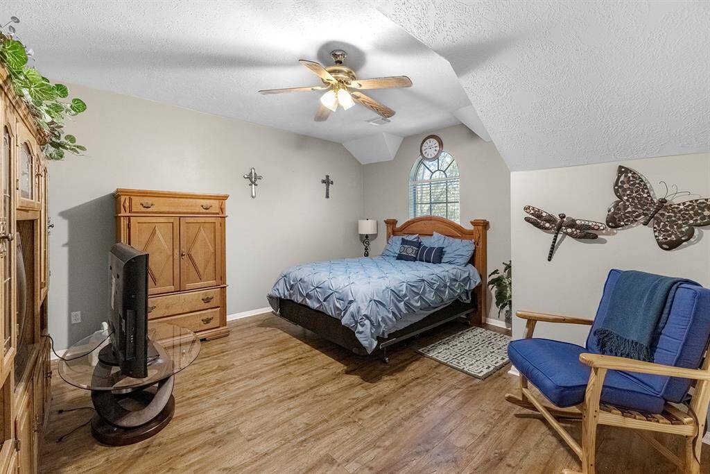 Cozy and inviting bedroom with warm wood flooring, stylish decor, and abundant natural light. Perfect for relaxation and comfort.