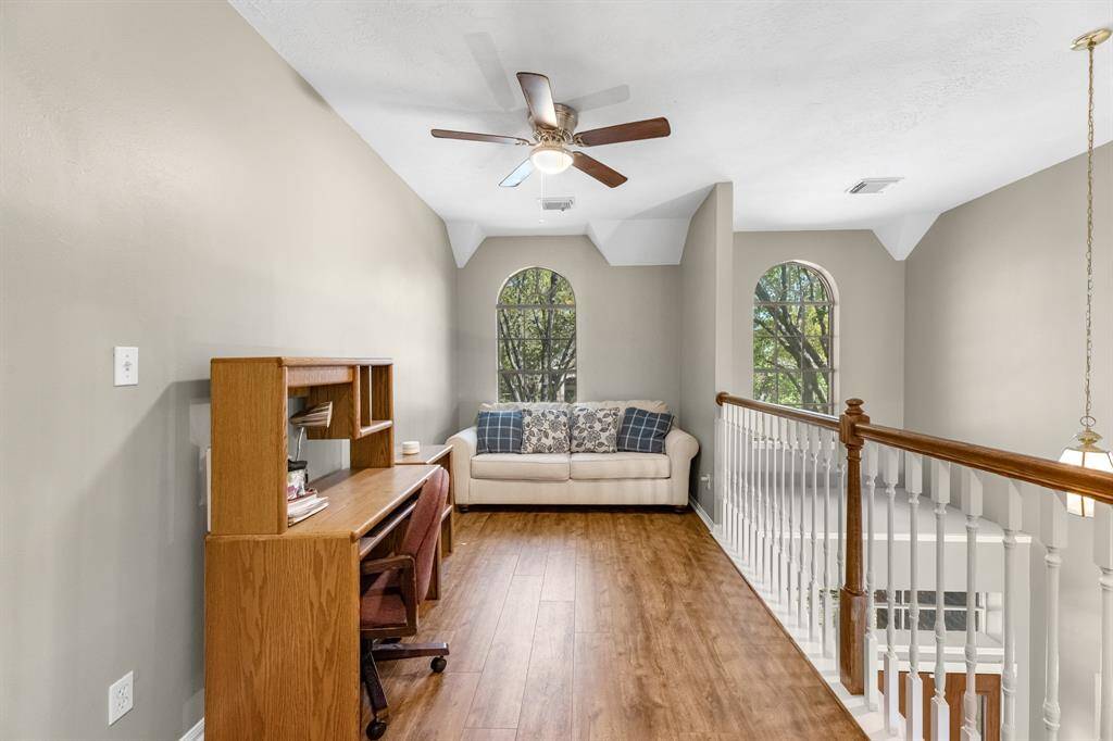 Imagine relaxing in this bright, inviting space with elegant arched windows and warm wood flooring. Perfect for a cozy reading nook or home office.
