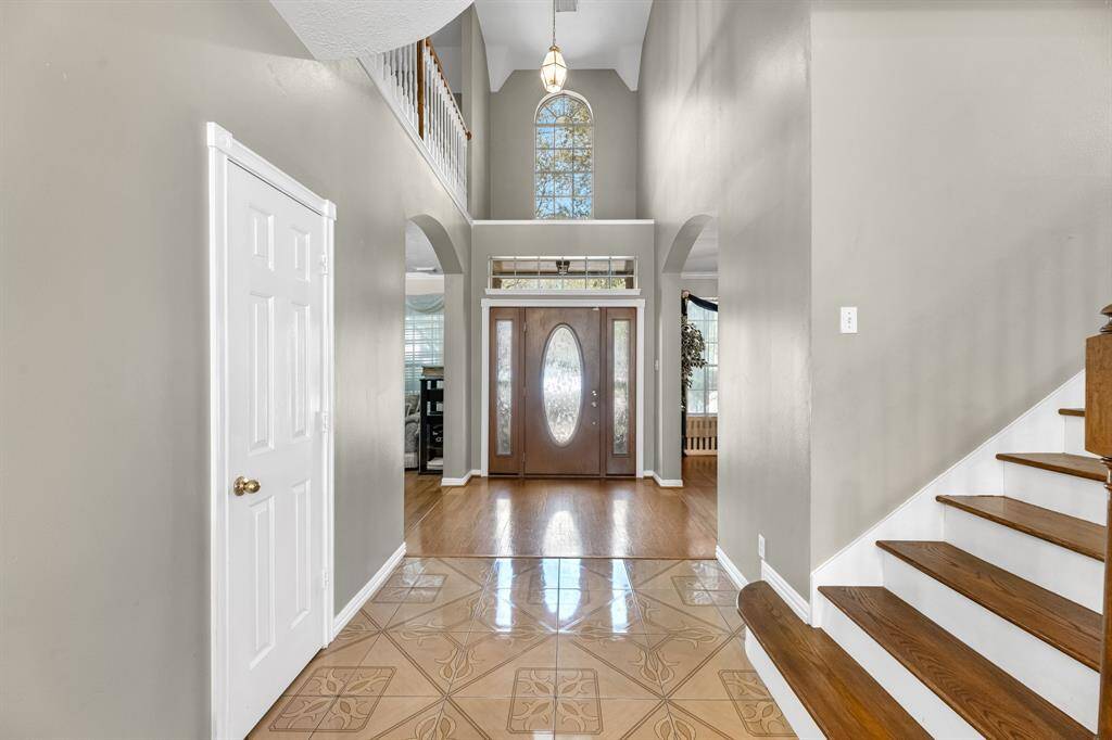 Welcome to your future home! This elegant entryway, with its soaring ceilings and gleaming floors, sets the tone for a warm and inviting living space.