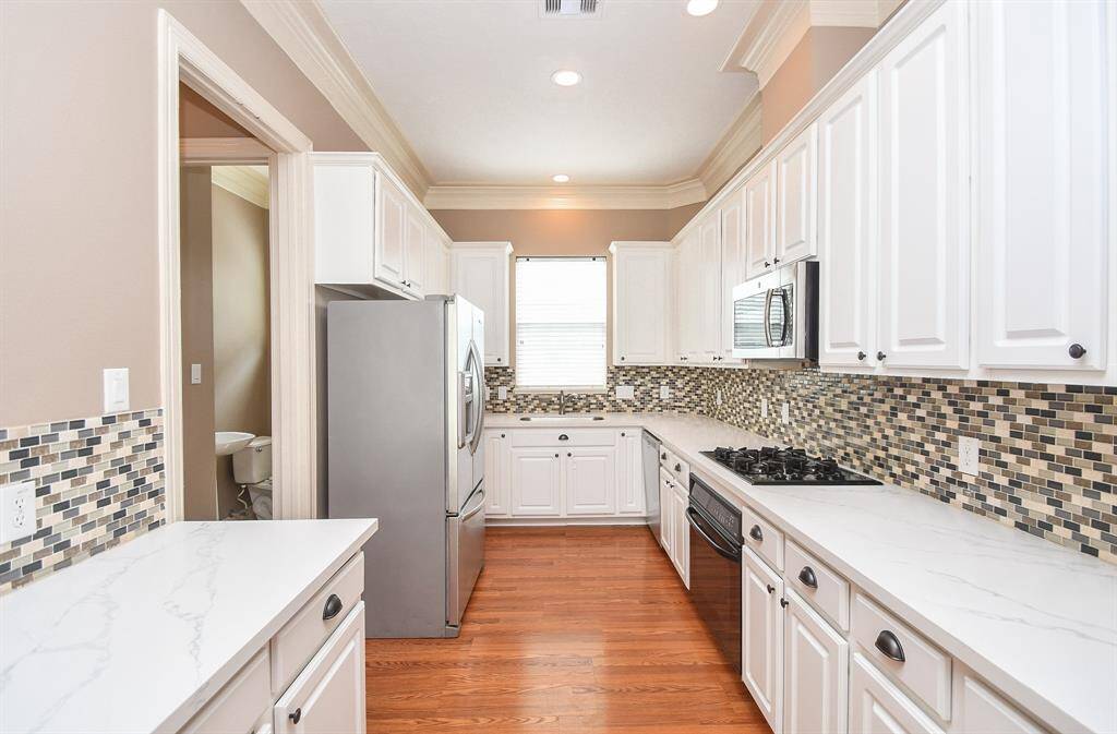 What a truly workable and beautiful 'workshop' for any cook or host! Wide traveling paths are lined with tons of gorgeous white cabinetry, up and down, quartz ? counter tops everywhere your tasks take you; lovely mosaic patterned tile backsplash and a big window over the sink, center.