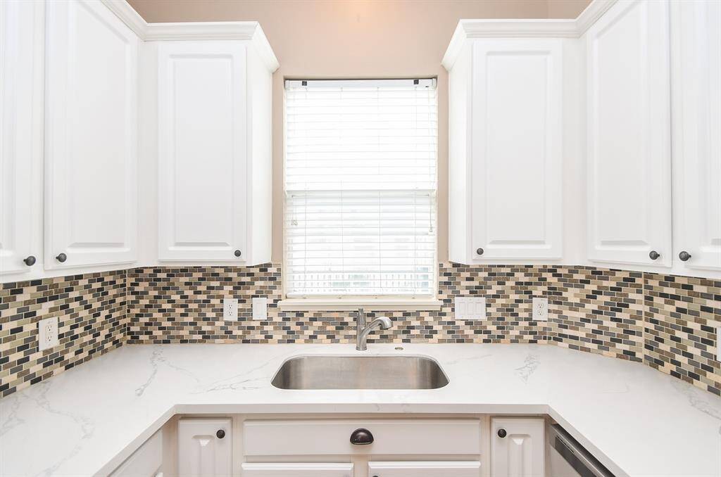 A generous farmhouse style stainless steel sink sits just below a welcomed window.