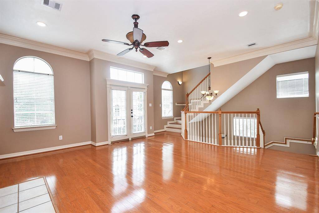Shining wood floors are complemented by a high ceiling, coffee toned walls/crown molding, and the satisfying visual continuity of the trim staircase.
