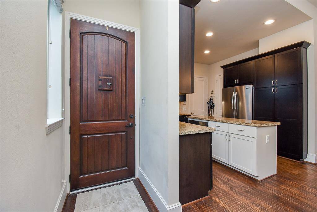 Cool tones grace the walls and complement the wood floors in this inside view of the front entry, with direct access to the kitchen.