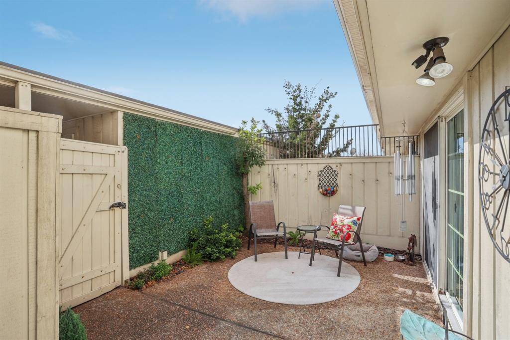 Fenced in back patio with a door leading to the 1-car garage and carport.