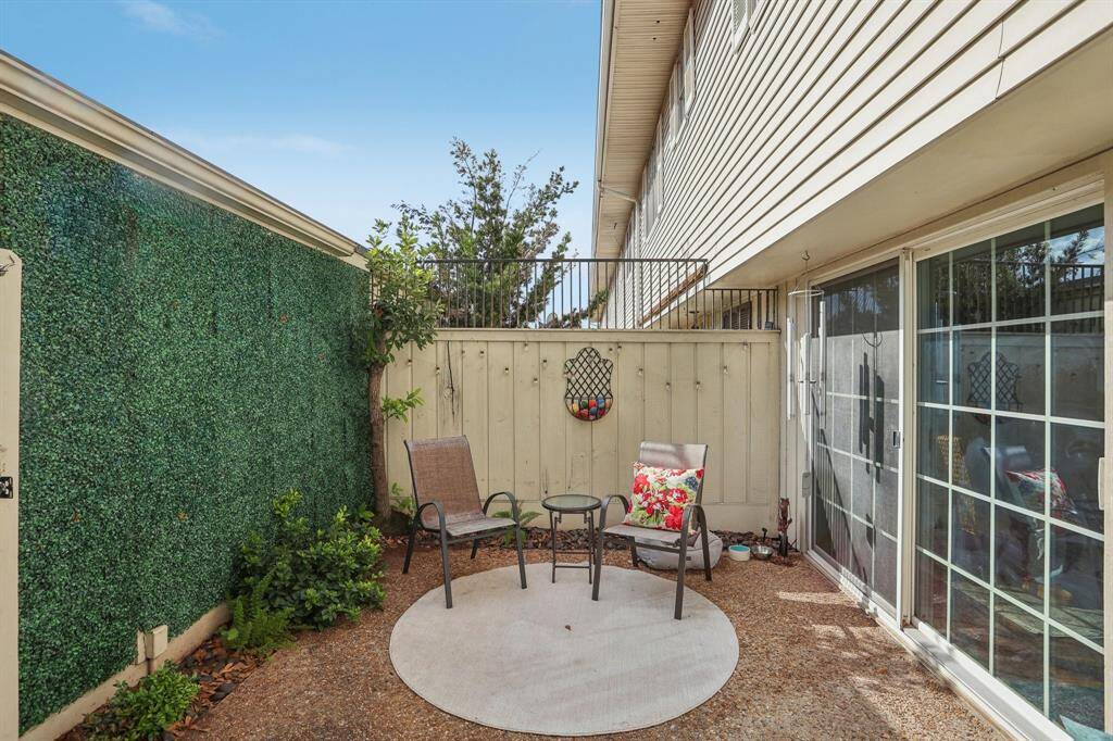 Fenced in back patio with a door leading to the 1-car garage and carport.