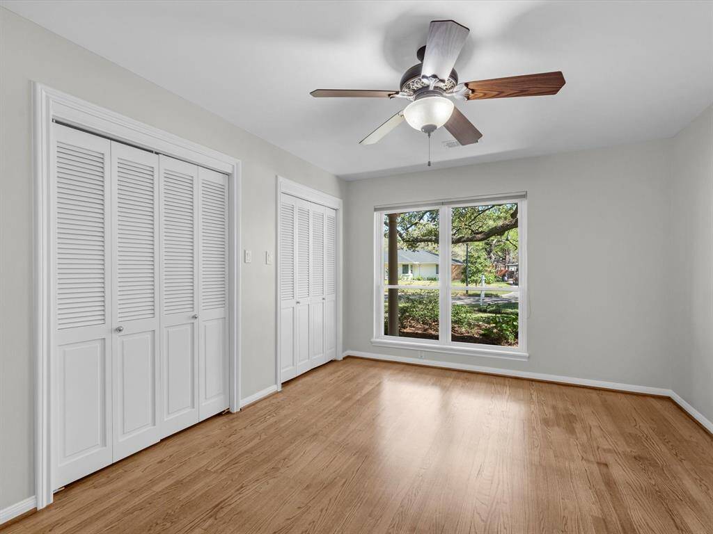 This inviting bedroom offers a picturesque view of the front yard, complemented by elegant hardwood floors throughout the home.