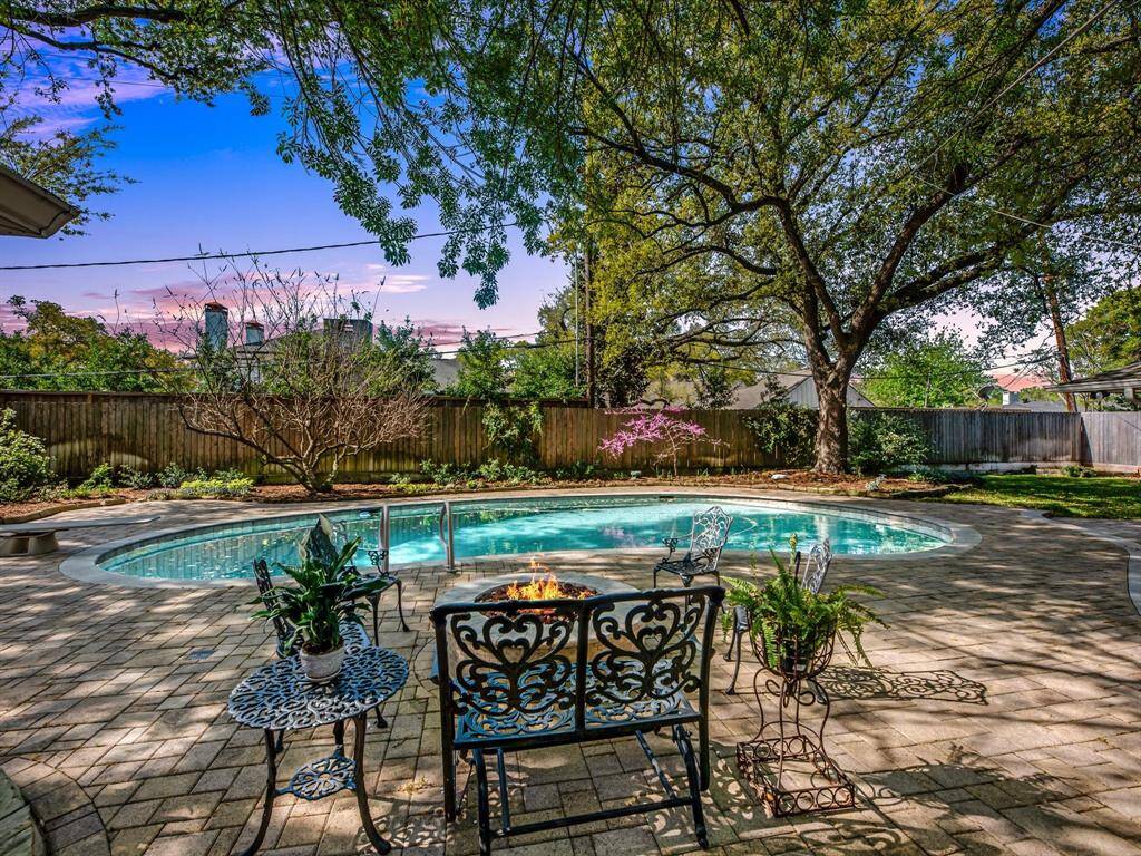 Serene twilight view of the pool with a cozy fire pit, perfect for evening relaxation.