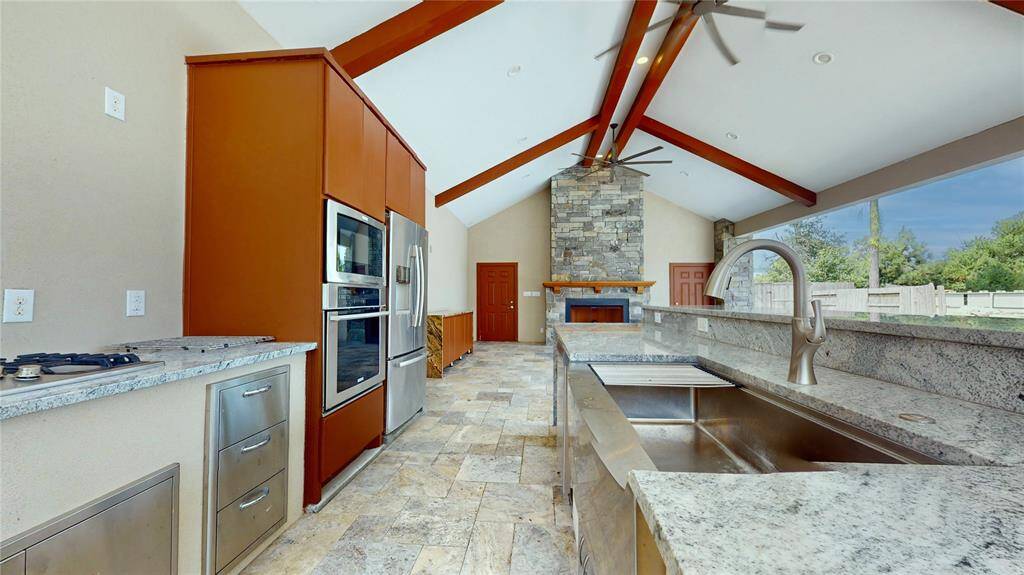 The complete outdoor kicthen includes a full size refrigeratot, oven, microwave, gas stove, a green egg and grill