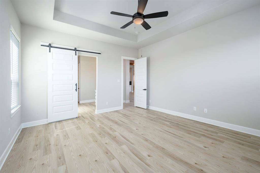 The private primary bedroom is nestled away from the secondary bedrooms and features a beautiful barn door and high ceilings.
