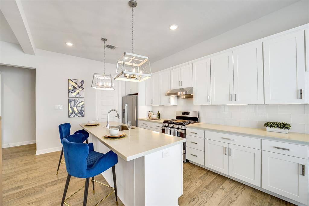 The modern kitchen features a spacious island, sleek quartz countertops, stainless steel appliances, under-cabinet lighting, & ample storage. Great for both everyday living & entertaining.