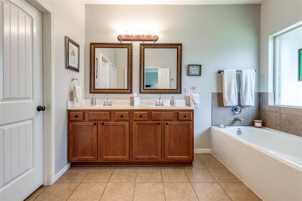Double vanities and soaking tub in the primary bathroom. Water closet to the left.