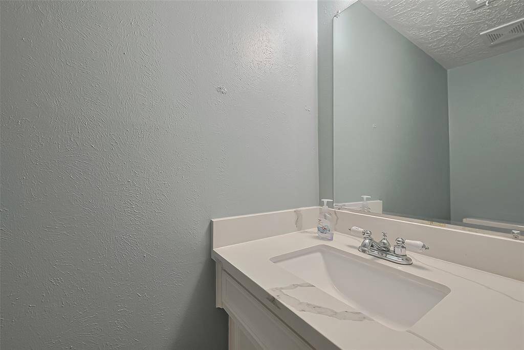The half bath with a compact vanity delivers style and efficiency. The mirror and cabinetry make the most of the space without compromising design.