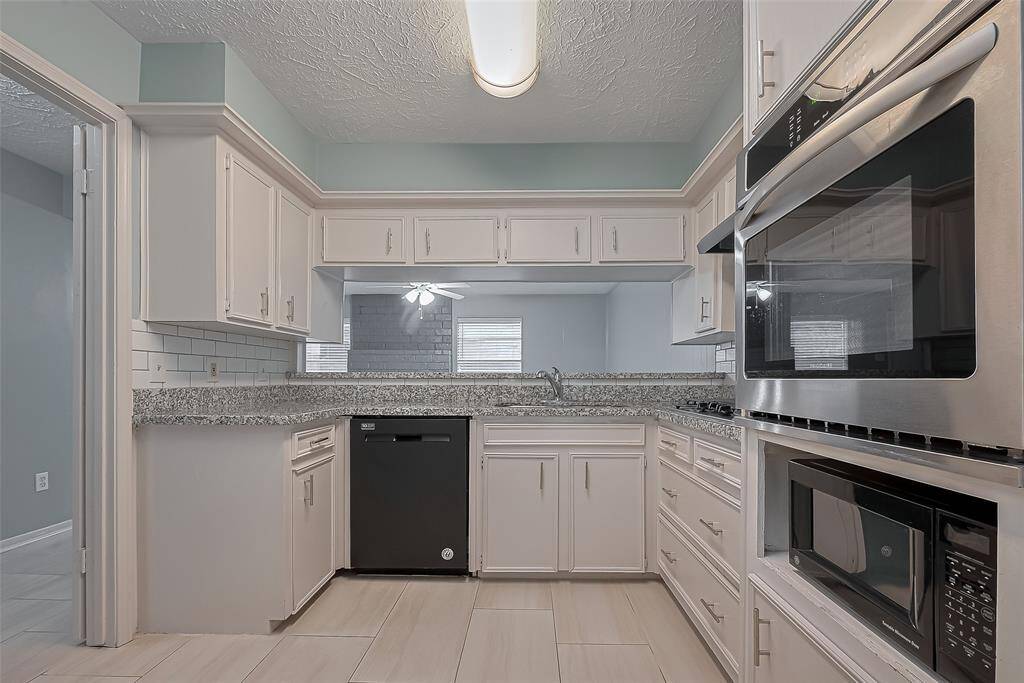 The kitchen boasts an impressive array of crisp white cabinetry, perfect for storage and prep. A raised bar beneath a wall cutout overlooks the dining area, adding both openness and connectivity.