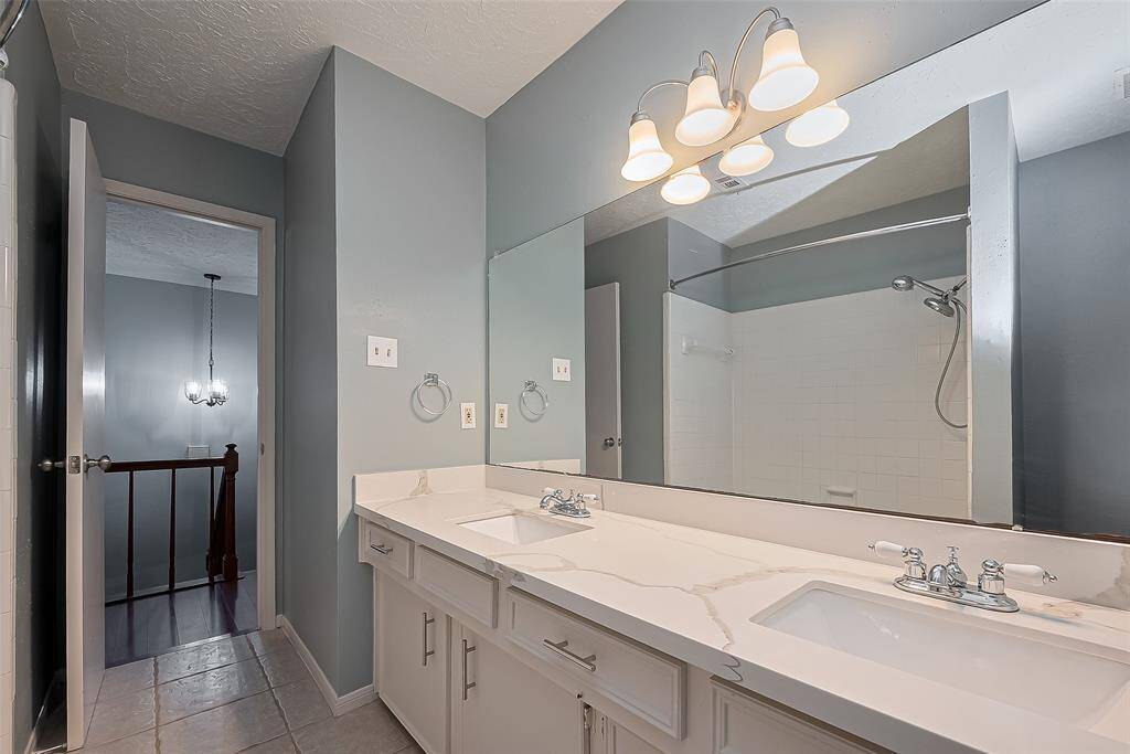 The primary bath features an expansive dual-sink vanity and a wall-length mirror. A shower-tub combination completes the space with added versatility.