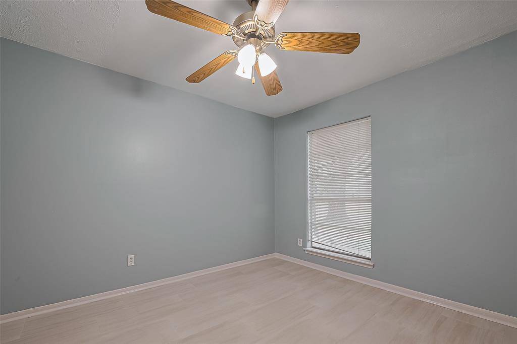 Dressed in light neutrals and grounded by pale flooring, this bright bedroom offers a peaceful retreat, complete with a large window, ceiling fan, and closet.