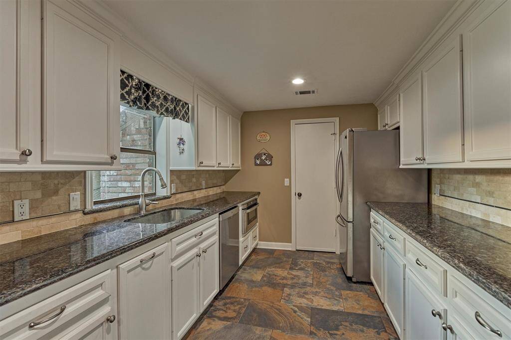 A closer look at the kitchen reveals a window over the sink with a view of the front yard. Just beyond, a pantry with shelving offers great storage.