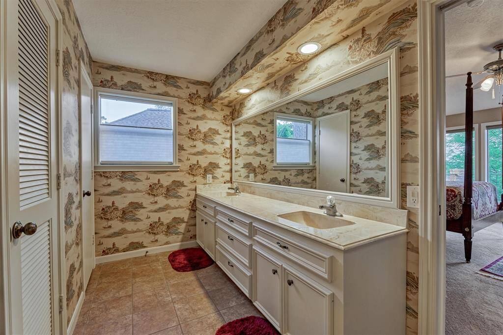 The bathroom also features dual sinks and a spacious vanity with ample counter space and storage. A window brings in natural light, creating a bright and welcoming atmosphere.