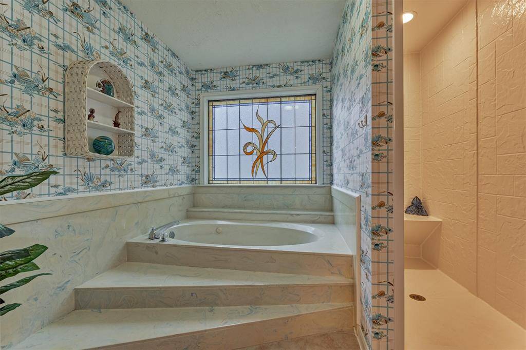 This bath features a large soaking tub and separate shower. Built-ins near the shower offer convenient storage for toiletries and towels.