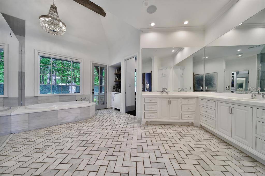 Gorgeous primary bathroom with double sinks, dual shower heads, bathtub, coffee bar, and two closets.