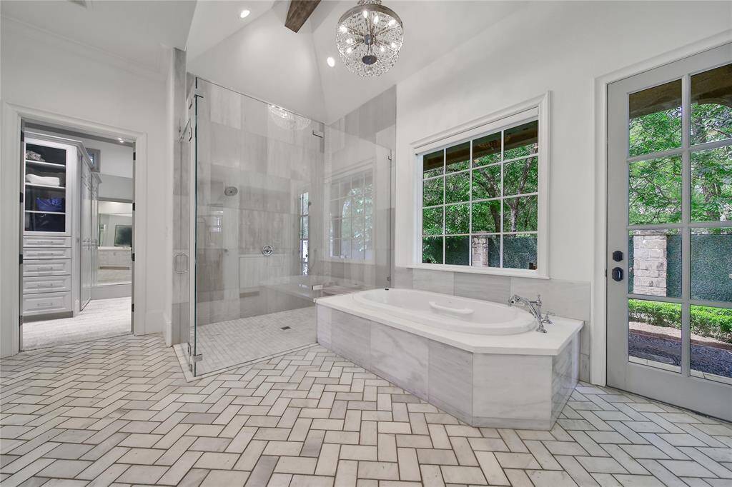 Gorgeous primary bathroom with double sinks, dual shower heads, bathtub, coffee bar, and two closets.