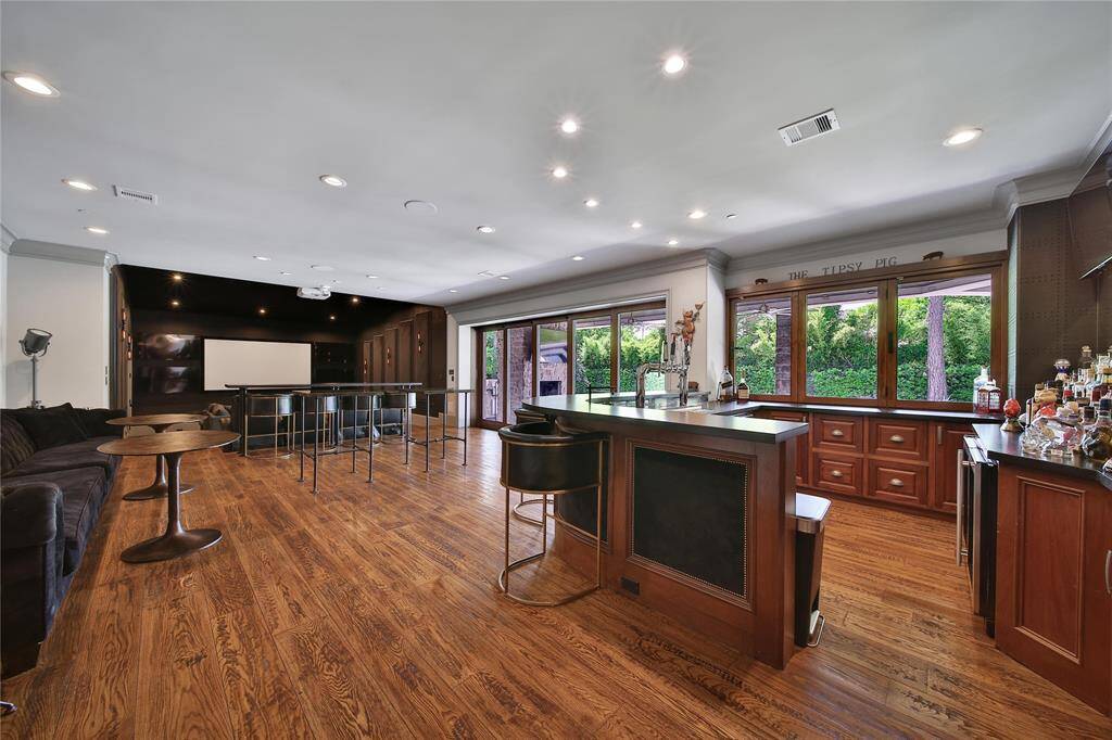 Ultimate entertainer's room featuring a full bar  TVs all around, perfect for hosting unforgettable gatherings.