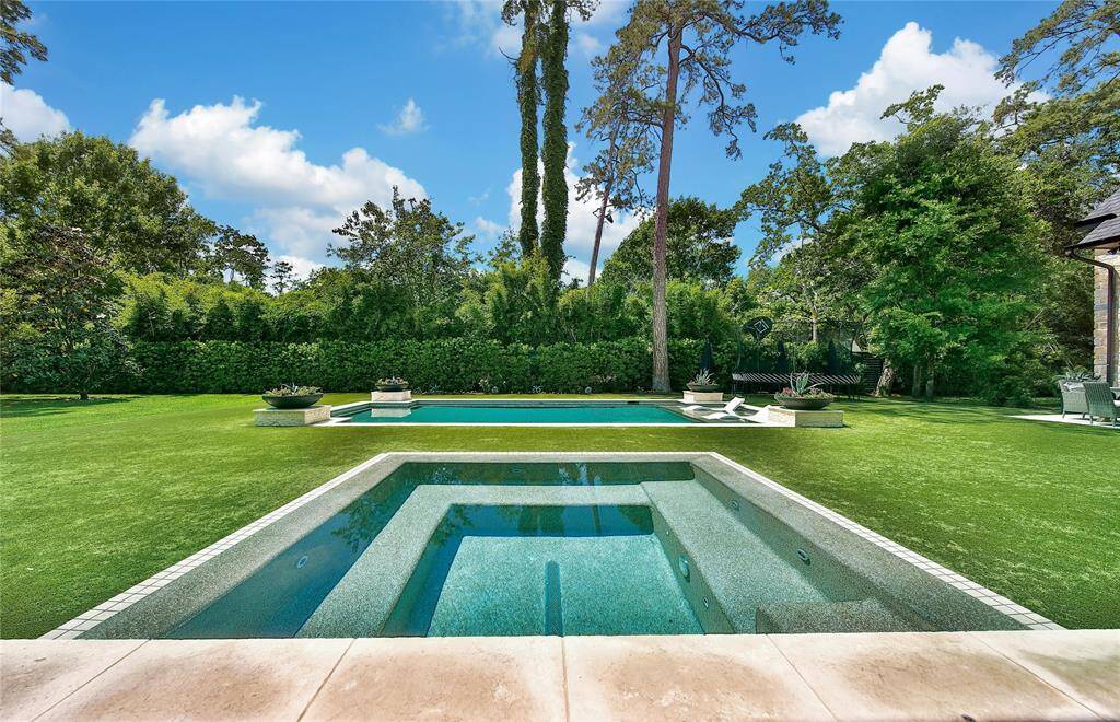 Infinity-edge hot tub and pool overlooking a beautiful turf yard.