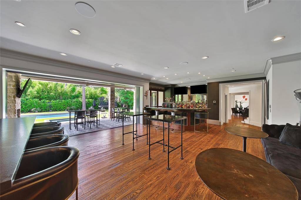 Ultimate entertainer's room featuring a full bar  TVs all around, perfect for hosting unforgettable gatherings.