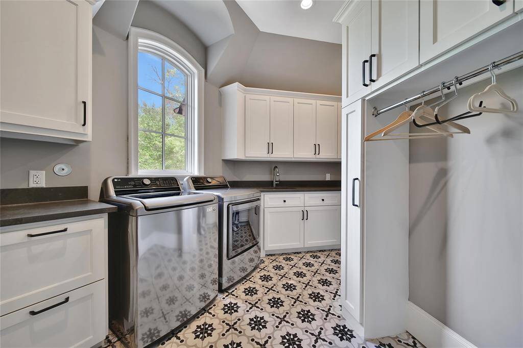 Upstairs laundry room equipped with drying rack and ample storage.