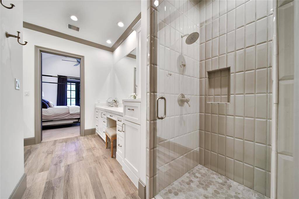 Upstairs primary bathroom with glass shower, double sinks, and spacious walk-in closet.