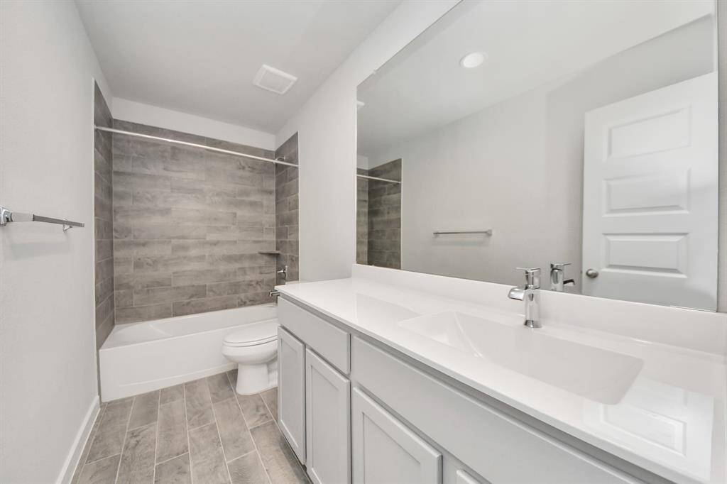 Secondary bath features tile flooring, bath/shower combo with tile surround, light stainedwood cabinets, beautiful light countertop. Sample photo of completed home with similar floor plan. Actual colors and selections may vary.