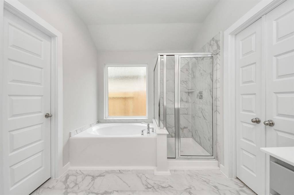 Indulge in a spa-like retreat within the confines of this primary bathroom.Delight in a spacious walk-in shower enveloped in stylish tile surround, and unwindin a separate garden tub adorned with custom detailing. Sample photo of completed home with similar floor plan. Actual colors and selections may vary.