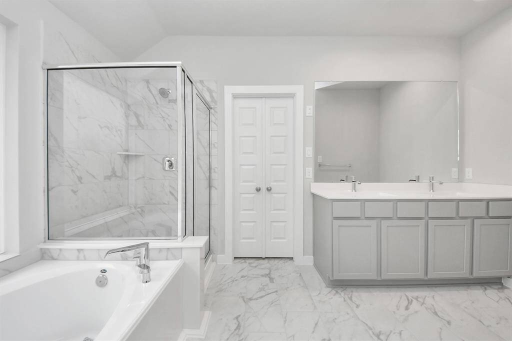 This additional view of the primary bath features a walk-in shower with the tile surroundand separate garden tub perfect for soaking after a long day. Sample photo of completed home with similar floor plan. Actual colors and selections may vary.