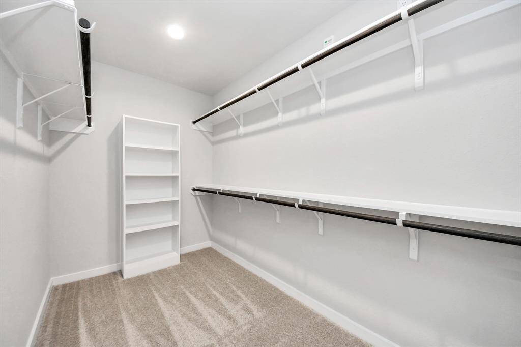Walk-in closet that epitomizes luxury and practicality. This generously sizedspace features built-in shelving, offering abundant room for impeccableorganization. High ceilings and recessed lighting create a bright andwelcoming ambiance. Sample photo of completed home with similar floor plan. Actual colors and selections may vary.