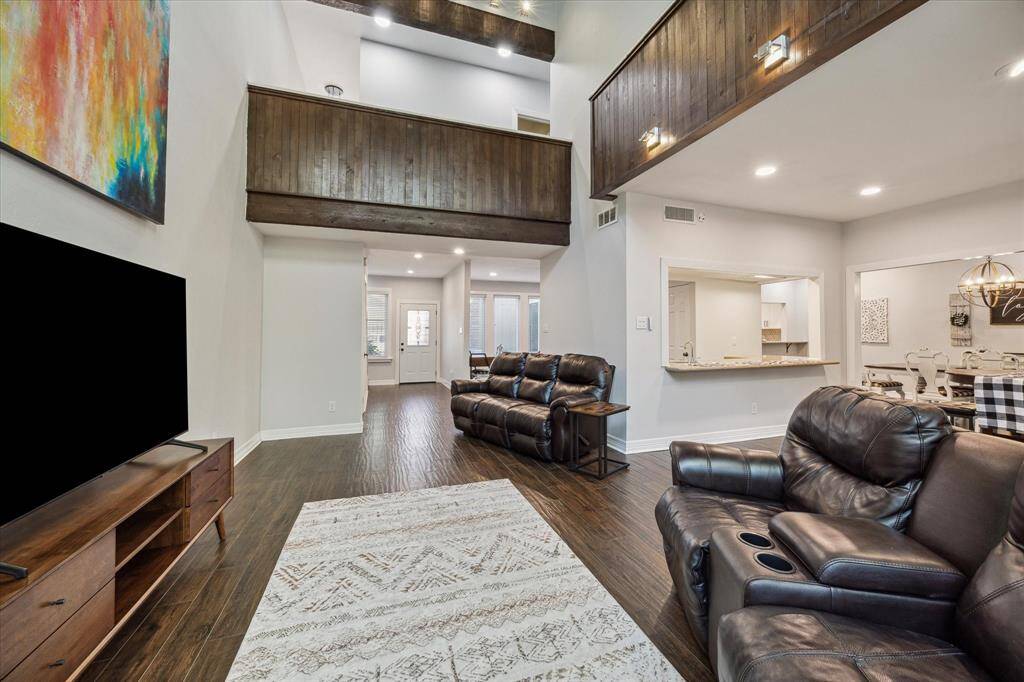 The living room has high ceilings and dark wood accents and is open to the wet bar and living area.