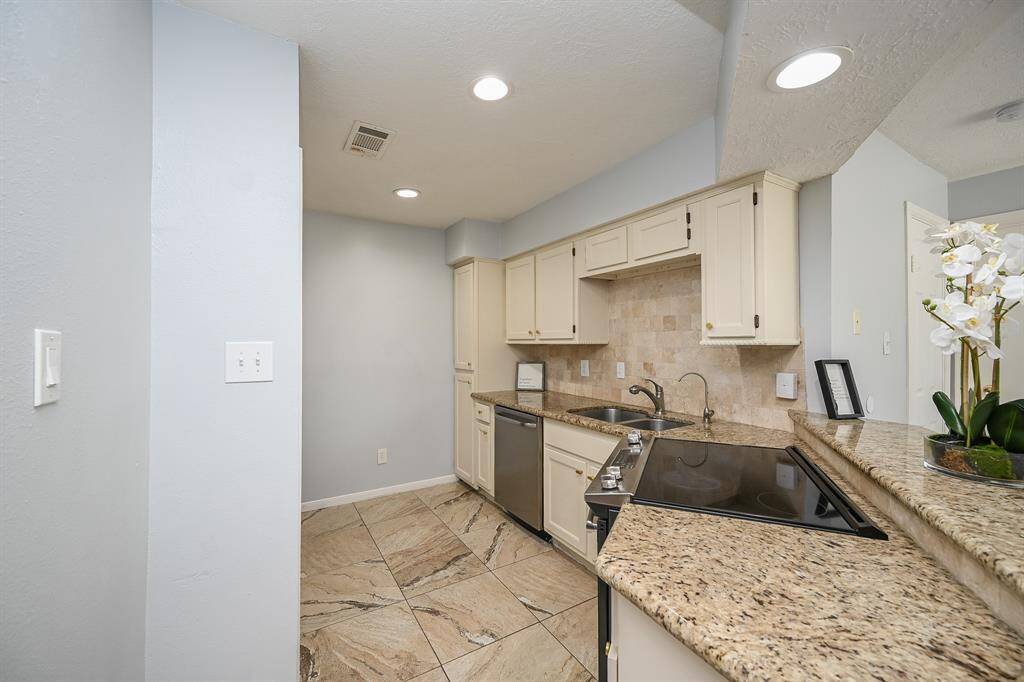 This kitchen features stone tile backsplash,recessed lighting, with a bar area perfect for quick meals or entertaining.