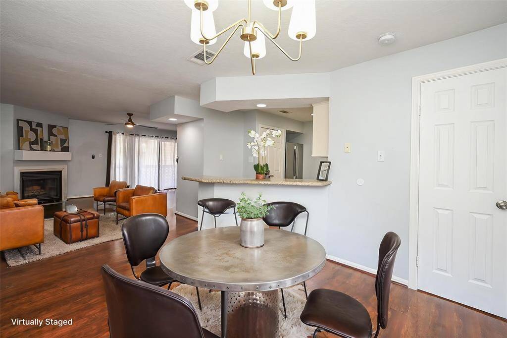 This open-concept living and dining area with hardwood floors. The living room includes a fireplace and large windows with curtains, offering natural light.