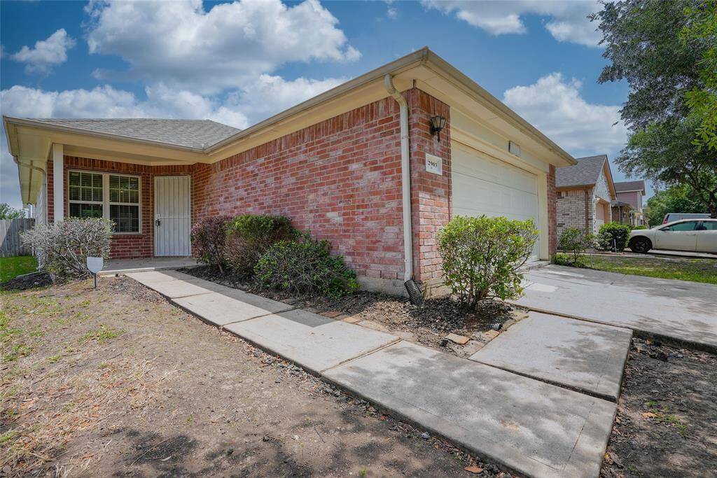 This photo shows a single-story brick house with a two-car garage. It features a clean driveway, a small front yard with some shrubs, and a welcoming front entrance. The neighborhood appears quiet and well-maintained.
