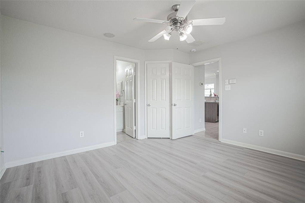Bright and airy room with light gray flooring, a ceiling fan, and neutral walls. Features a closet and access to a bathroom and adjacent room, perfect for a bedroom or office space.