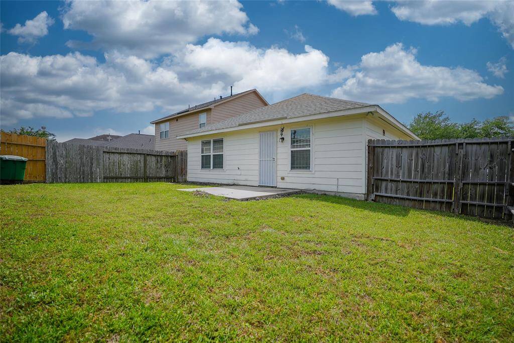 Cozy single-story home with a fenced backyard, featuring well-kept grass and a small patio area. Ideal for outdoor activities and relaxation.