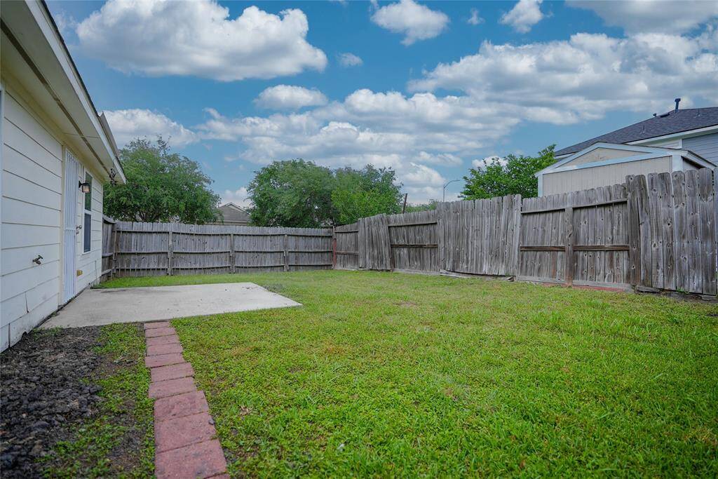 This photo shows a fenced backyard with a small patio area and well-maintained grass, perfect for outdoor activities and privacy.