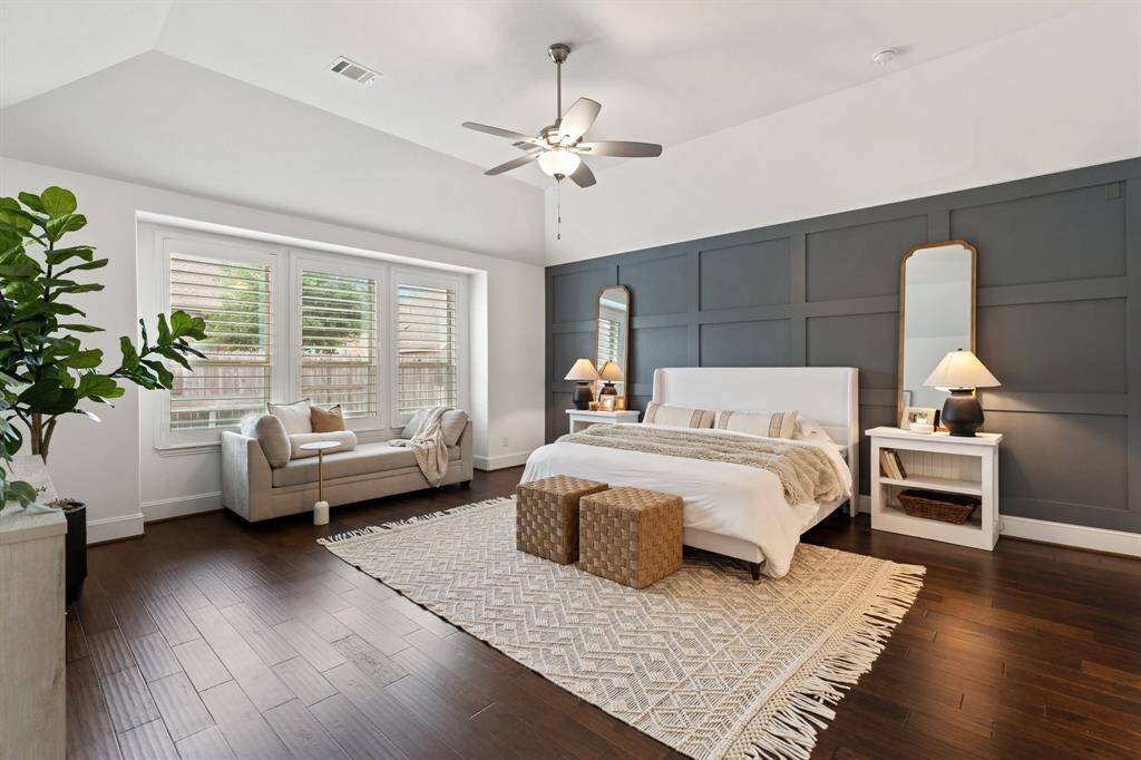 The first floor primary suite offers raised ceilings, custom millwork, and room for a sitting area.