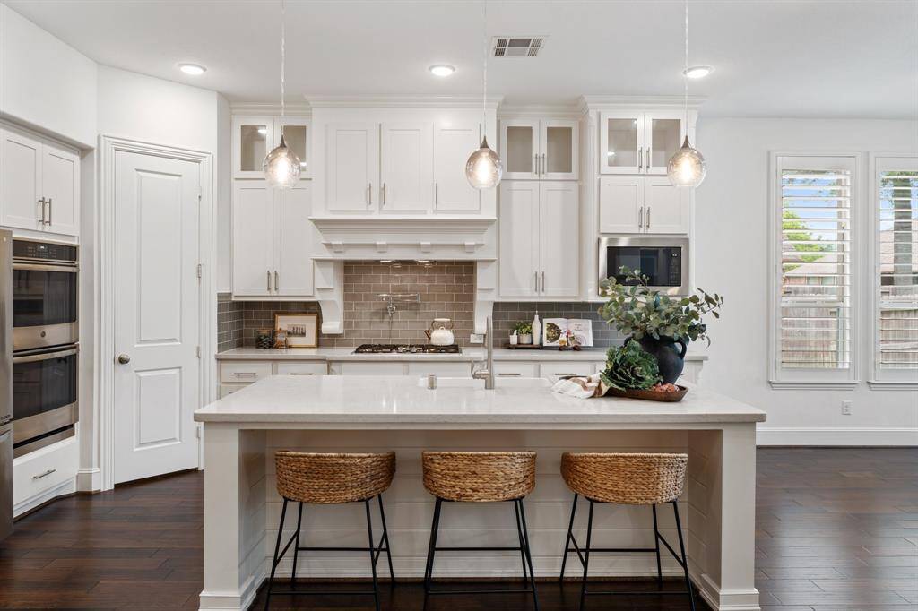 This kitchen is a culinary dream, equipped with high-end appliances, double ovens, a pot filler, and a large island with plenty of space for meal prep and gatherings.
