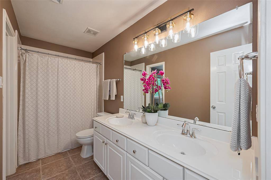 Shared bathroom with shower/tub combo and double sinks.
