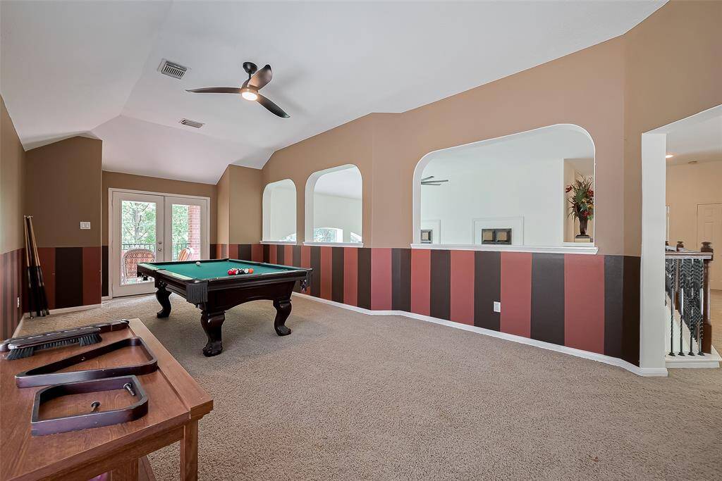 Upstairs game room with enough space to put a pool table and sofas/other furniture. This angle looks out to the balcony/covered patio.
