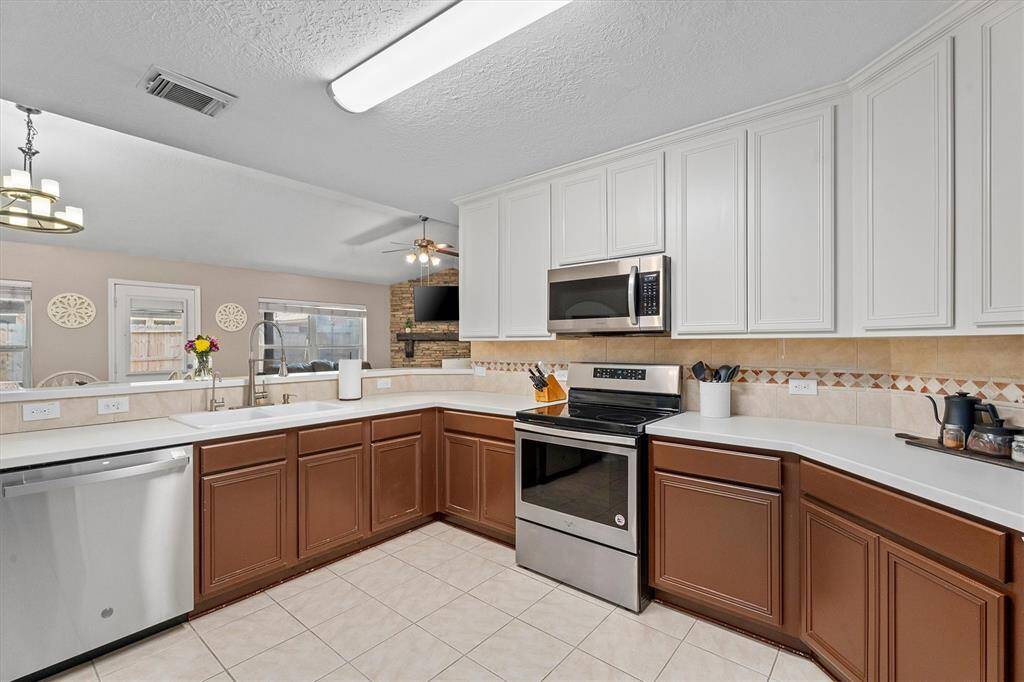 Open kitchen with custom painted cabinets, hardtop counters, large pantry and stainless appliances