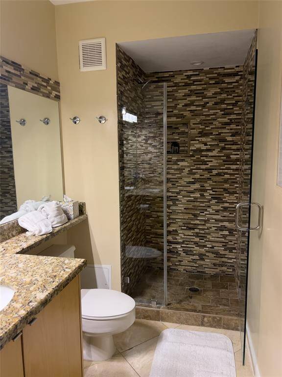 Modern bathroom featuring a glass-enclosed shower with mosaic tilework, a granite countertop with a built-in sink, and a neutral color palette.