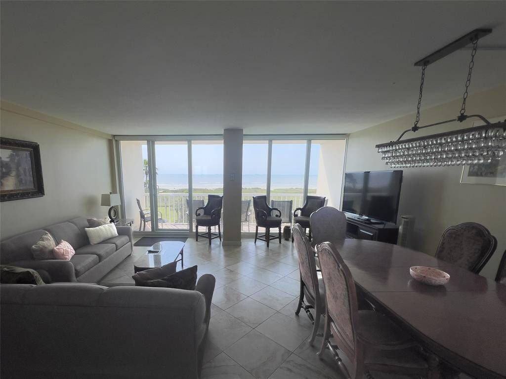 This spacious living and dining area features large windows offering stunning ocean views. It includes comfortable seating, a TV, and a stylish dining table, creating a perfect space for relaxation and entertaining.
