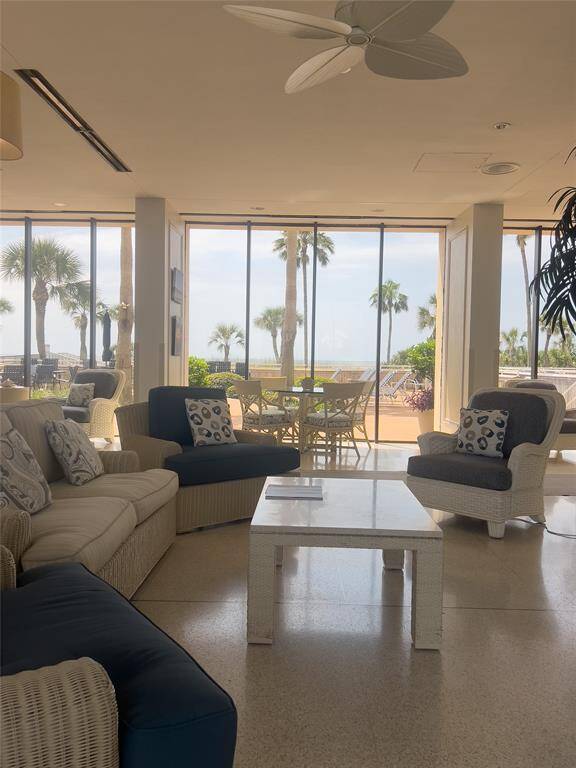 Bright, open lobby of the building with large windows offering stunning views of palm trees and the ocean. Features comfortable seating, a ceiling fan, perfect for relaxation and entertaining guests.