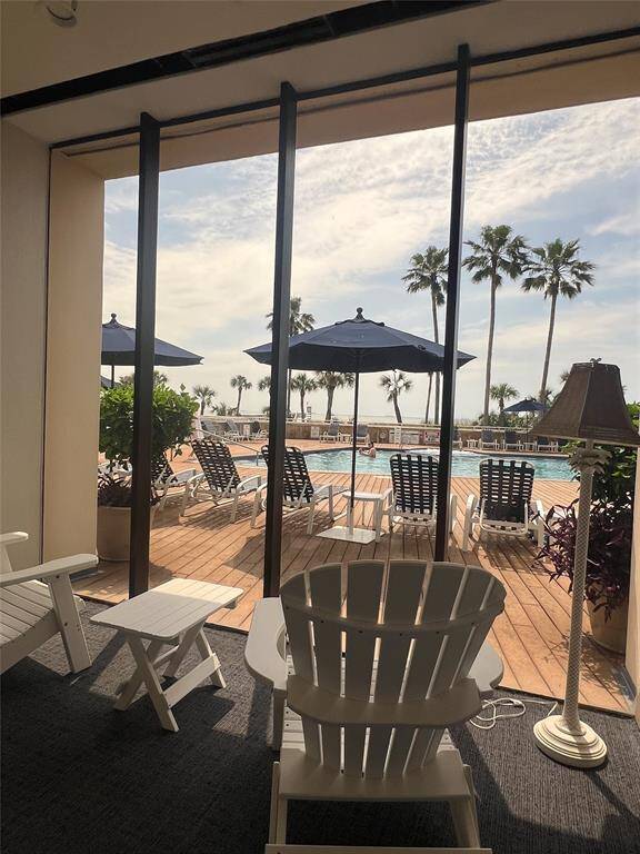 Another view of the property lobby space whjich features a cozy seating area with a view of a pool deck, complete with sun loungers and umbrellas. Tall windows frame the scene, offering glimpses of palm trees and a serene, sunny ambiance—perfect for relaxation and enjoying outdoor leisure.